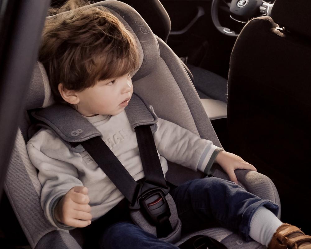 Un garçon assis et attaché dans le siège auto I-GUARD installé dans la voiture