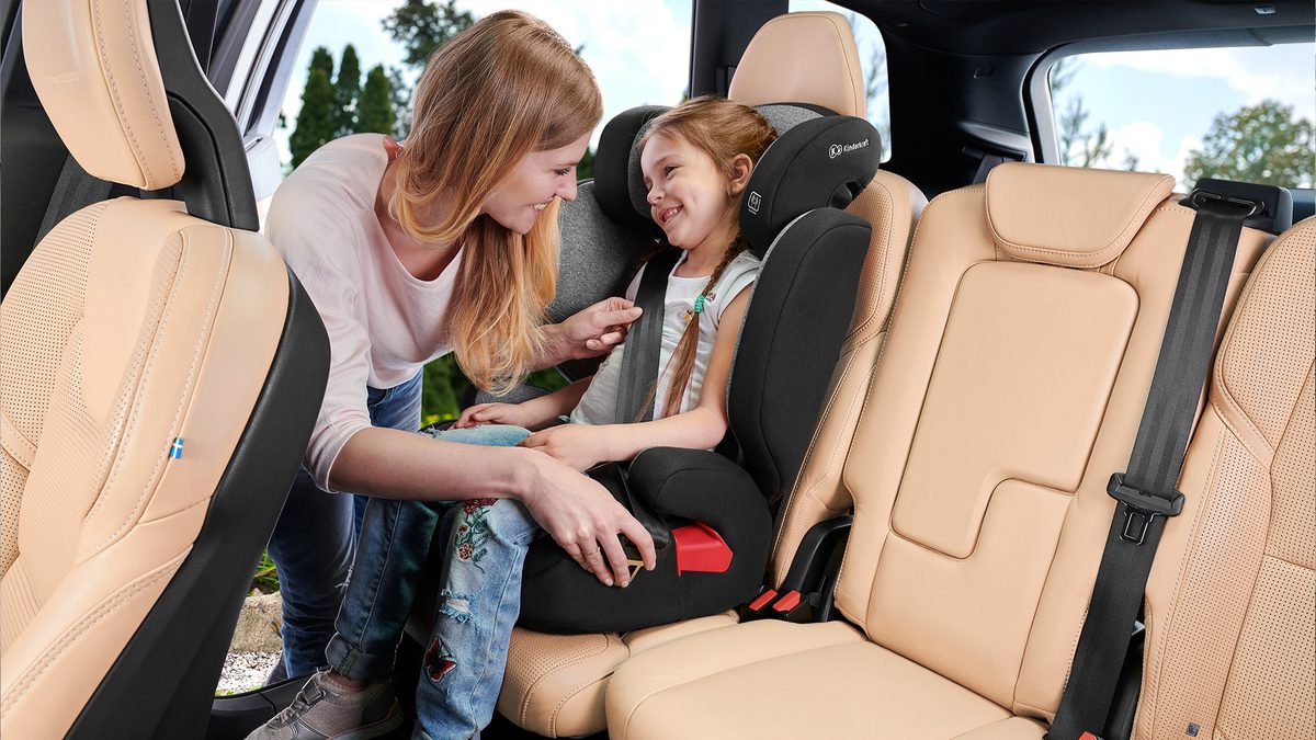 La fillette est assise dans la voiture dans le siège auto XPAND, la mère attache la ceinture de sécurité